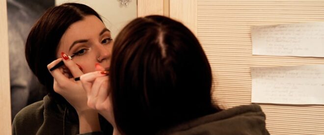 eyeliner styles woman applying eyeliner in the mirror