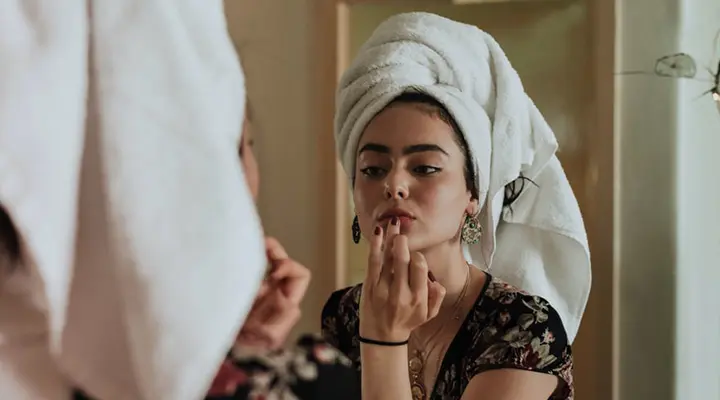 woman applying makeup in the mirror