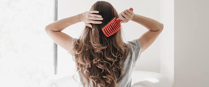 woman brushing her long curls out with hair brush