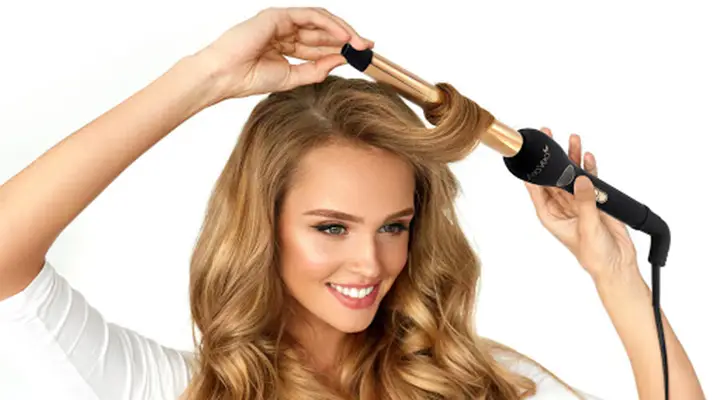 woman curling her long hair with curling iron