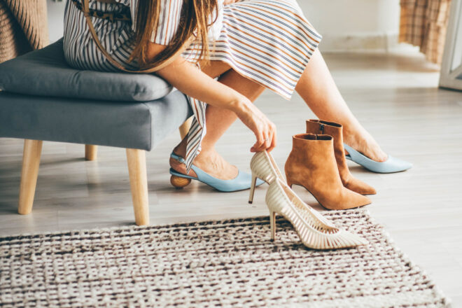 Fashionable young woman in striped dress trying new shoes while