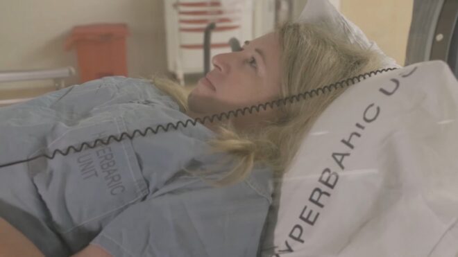 A woman lying in a hyperbaric chamber during an oxygen therapy session